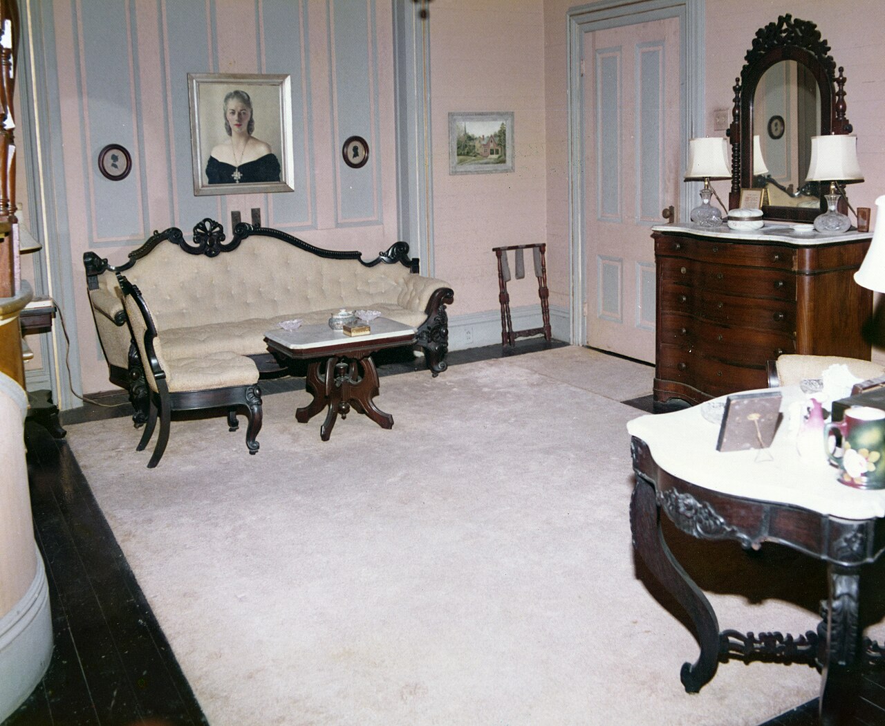 Archival photograph of a sofa, framed portraits, decorative wall panels and antique furniture inside the Otto house