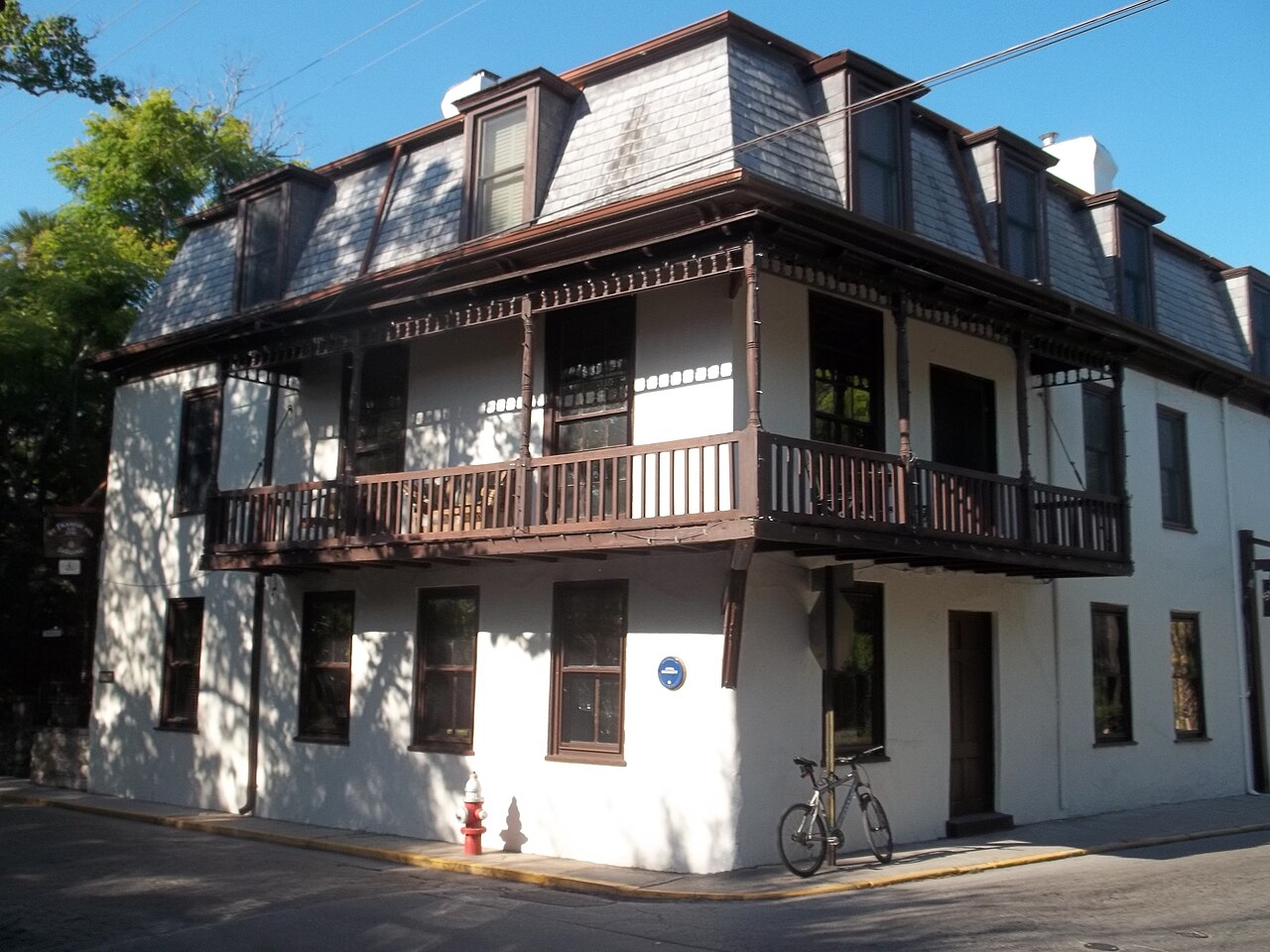 St. Francis Inn at a street corner with a shaded wooden balcony and mansard roof